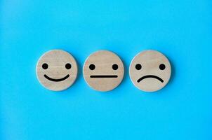 neutrale, gelukkig en verdrietig emotie gezichten Aan houten kubussen. klant tevredenheid en evaluatie concept foto