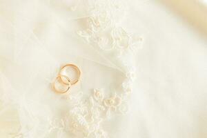 twee goud bruiloft ringen liggen Aan de bruid geborduurd tule met zacht plooien. mooi bruiloft achtergrond. lay-out voor ontwerp. een ansichtkaart. foto