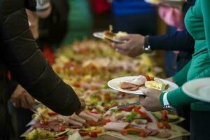 buffet. handen met een bord Aan de achtergrond van een tafel met voedsel. foto