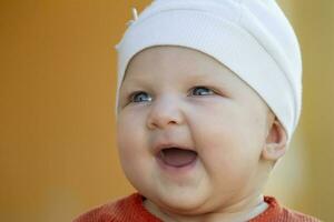 de gezicht van een zes maanden oud vrolijk baby. gelukkig baby in een hoed. foto