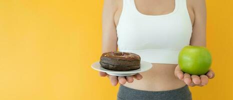 slank lichaam Dames Kiezen gedurende groen appel en chocola donut, vrouw Kiezen groen appel voor eetpatroon. mooi zo gezond voedsel. gewicht verliezen, evenwicht, controle, verminderen dik, laag calorieën, routines, oefening. foto