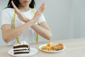 schoonheid slank vrouw lichaam verwarren dik voedsel. vrouw in restaurant behaalt gewicht verlies doel voor gezond leven, laag calorie, dun taille, voedingsdeskundige. eetpatroon, lichaam vorm geven aan, balans controle, voorkomen, voedingswaarde foto