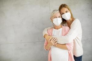 rijpe moeder en dochter knuffelen met maskers met kopie ruimte foto