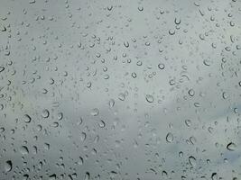 achtergrond van regen druppels Aan glas met blauw lucht en wit wolken. foto