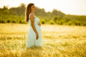 zwangere vrouw in veld in zonlicht foto