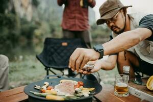 selectief focus van mannetje hand- terwijl Koken steak in kamp foto