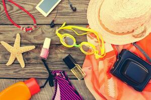 zomer vrouwen strand accessoires voor uw zee vakantie Aan de oud houten achtergrond. afgezwakt afbeelding. foto