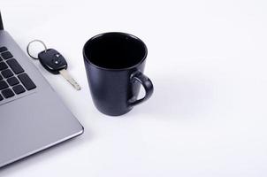 leven technologie concept met koffiekopje, autosleutels en laptop computer op witte achtergrond foto