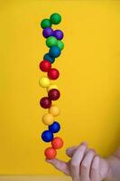 balanceren gekleurde plastic ballen Aan een vinger Aan een geel achtergrond. foto