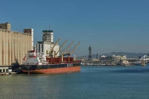 havenkraan laadt een container op de pier voor transport van import export en bedrijfslogistiek in barcelona, spanje foto