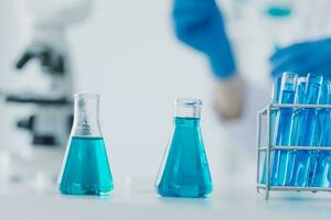 hand- van wetenschapper met test buis en fles in medisch chemie laboratorium blauw banier achtergrond foto