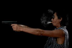 portret Aziatische oude man met een pistool-pistool op een zwarte achtergrond foto