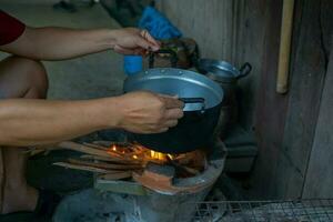 dorpelingen zijn Koken voedsel van een houtgestookt koperslager. de bodem van de pot heeft zwart roet terwijl Koken. de koperslager brand is nog steeds gebruikt in landelijk Keukens in de noorden en noordoosten van Thailand. foto