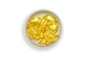 knipsel pad. goud vis olie gel capsules in kom geïsoleerd. vitamine e. aanvullend voedsel. capsules Zalm vis olie Aan top visie visie. omega 3. foto