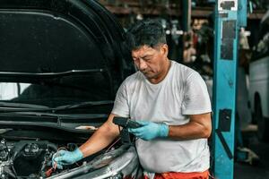 ervaren auto mechanica inspecteren auto accu terminals en Spanning naar identificeren de oorzaak van fouten of gebreken. uitvoeren diagnose, reparatie, vervangen, en verwijderen mechanisch en elektrisch componenten. foto