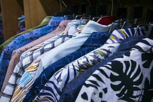 kleurrijk verscheidenheid van overhemden ophangingen in een kleding toonzaal. opsluiten focus foto
