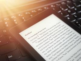 close-up van e-boeklezer met de Bijbel op een laptop toetsenbord met zonnestralen licht concept