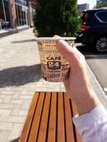koffie in een papieren beker in de hand van een vrouw op straat foto