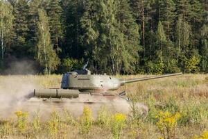 Moskou, Rusland, 25-08-2018, tentoonstelling van leger apparatuur, Scherm van leger uitrusting in actie. een leger tank in beweging tegen de achtergrond van groen bomen. foto