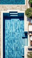 loungen door de zwembad met blauw en wit tegels, bijtend water, breking, antenne top visie. ai generatief foto