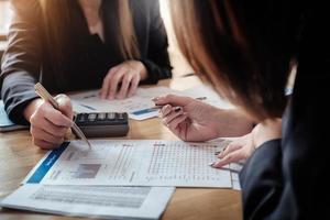 economische onderzoeksdiscussies, business team analyseert inkomensgrafieken en grafieken om marketingconcept te plannen met behulp van pen en rekenmachine voor analyse. foto