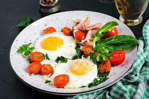 bord met een keto eetpatroon voedsel. gebakken ei, ham, spinazie, en tomaten. keto, paleo ontbijt. foto