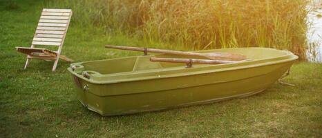 houten lounge stoel en een boot Aan de gras van de kust van kalmte meer foto