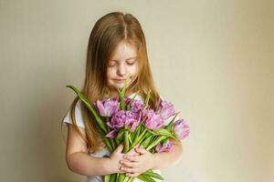 portret van weinig meisje met boeket van bloemen tulpen in haar handen foto