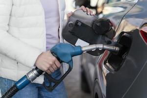 vrouw die de auto bij het benzinestation tanken foto