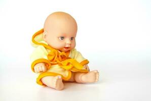 een speelgoed- baby in een helder dressing gewaad. pop Aan een wit achtergrond. foto