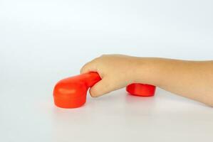 rood speelgoed- telefoon in de kind hand. detailopname van een kind hand. geïsoleerd Aan een wit achtergrond. de concept van een reclame spandoek. foto