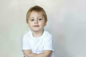 portret van een schattig weinig jongen in een wit t-shirt. kinderen emoties. kind Aan de achtergrond van de muur. succes, helder idee, creatief ideeën en concepten. foto