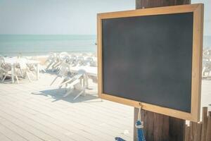 krijt bord met houten kader met zand strand achtergrond foto