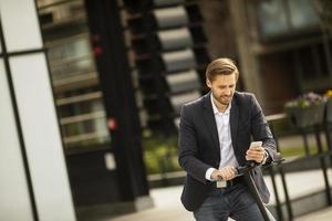 zakenman kijken naar telefoon op een scooter foto