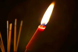 brandend wierook en rood kaarsen naar betalen hulde Aan een donker achtergrond gedurende hongerig geest festival betalen hulde naar hun overleden voorvaders foto