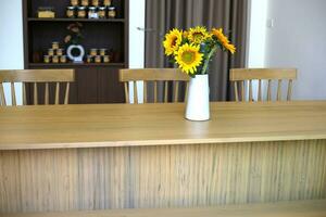 zonnebloem bloemen in vaas Aan houten tafel in cafe met zonlicht foto
