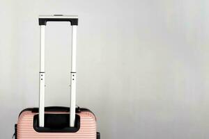 detailopname van perzik bagage tas, minimalistische reizen concept in perzik kleur. bagage cabine grootte karretje, grijs blanco achtergrond met ruimte voor tekst, vakantie reis, bagage koffer foto