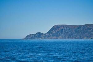 visie van de zee naar de west kaap in Noorwegen in zonneschijn. golven en rotsen foto