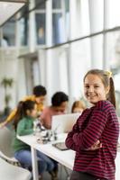 schattig klein meisje staan voor kinderen programmeren van elektrisch speelgoed en robots op robotica klas foto