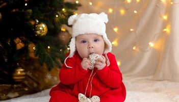 kerstkind dat naar de camera kijkt en een krans met hartjes vasthoudt foto