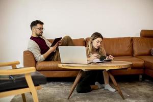 jonge vrouw en jonge man met behulp van laptop zittend op de bank thuis foto