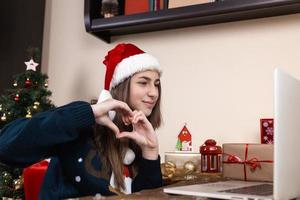 meisje in Kerstman hoed met behulp van laptop voor videogesprek met vrienden en ouders foto