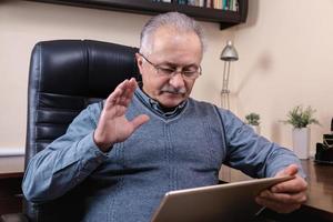 senior man leest nieuws op digitale tablet foto