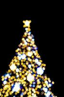 wazig lichten verhelderend de Kerstmis boom Aan een zwart achtergrond foto
