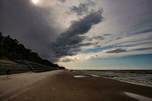 kust landschap met water golven, strand en dreigend donker bedreigend storm wolk in voorjaar foto