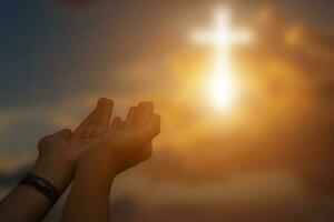 silhouet van christen Open handen naar bidden voor zegen van god Bij zonsondergang achtergrond. foto
