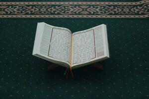 boef, Indonesië - 2022. een dichtbij omhoog van de heilig boek al-koran Aan een groen gebed tapijt. Islamitisch foto concept.