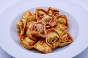 Italiaans tortelloni met tomaat saus en parmigiano reggiano kaas. foto