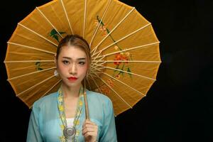Aziatisch vrouw in trekkracht kebaya achter paraplu Aan zwart achtergrond foto