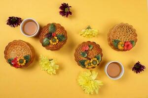 kleurrijk bloem versierd maan taart Chinese midden herfst thee in klein theekopje festival madeliefje chrysant mamma roos bloem rood geel roze Purper paars Aan geel achtergrond foto